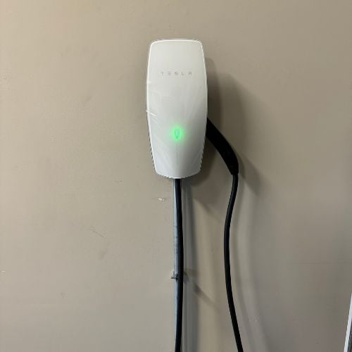 White Tesla wall charger with green power indicator light