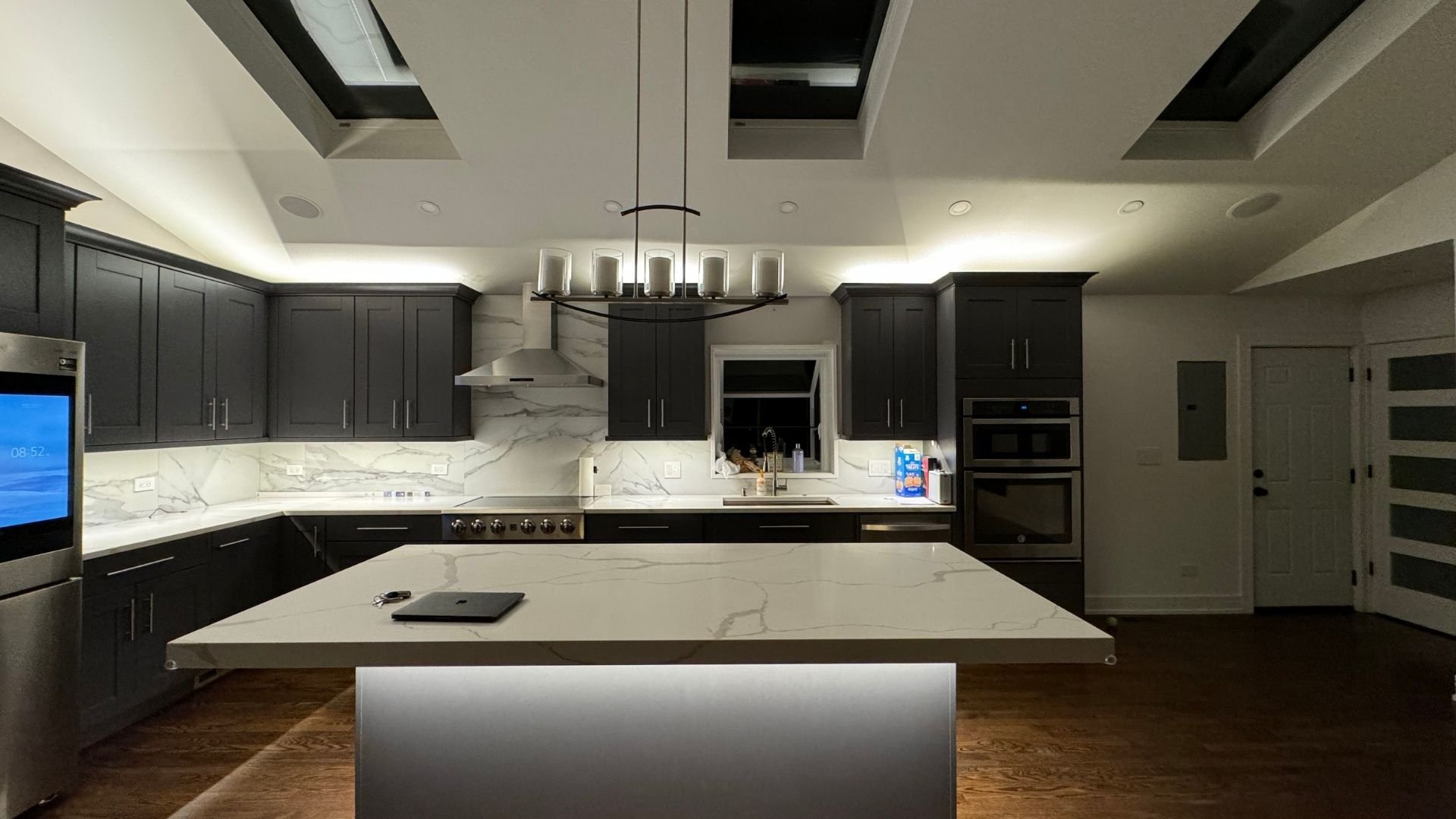 Modern kitchen with dark cabinets, marble countertops, and pendant lighting