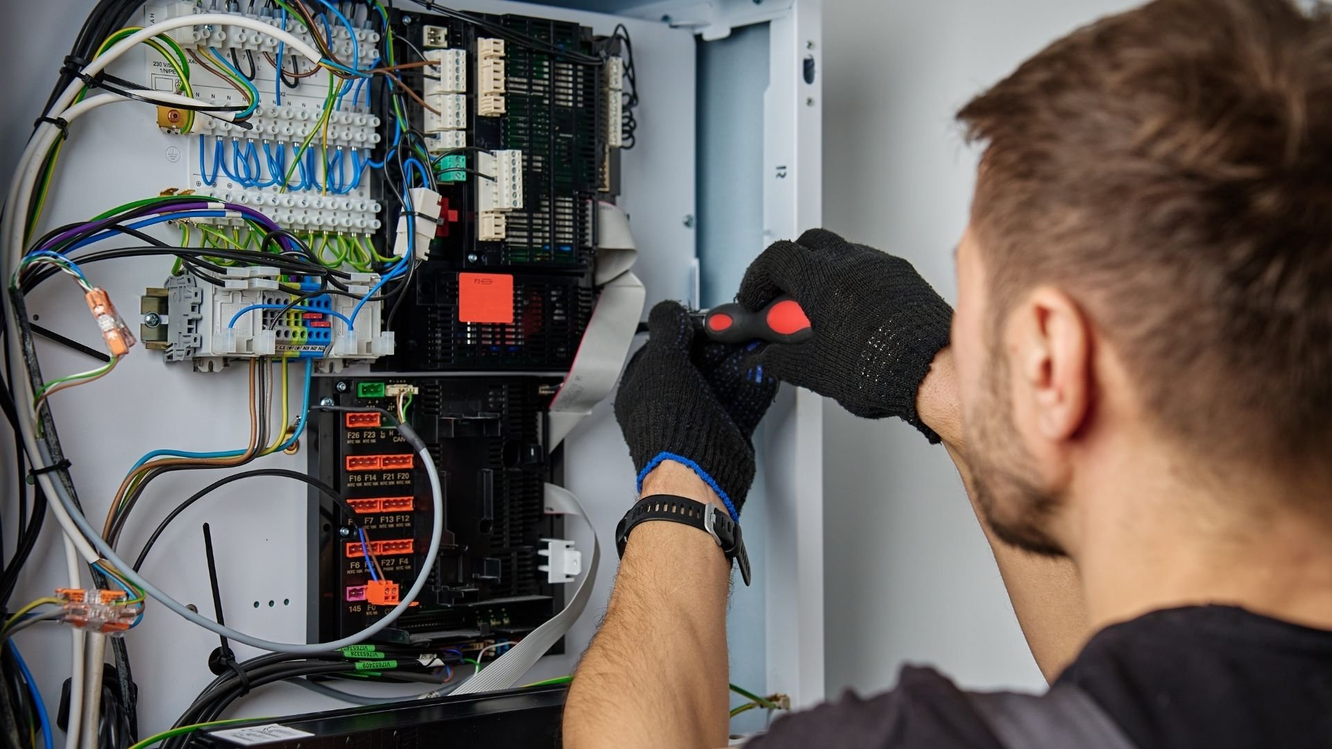 Technician checking electrical panel with complex wiring and circuit breakers